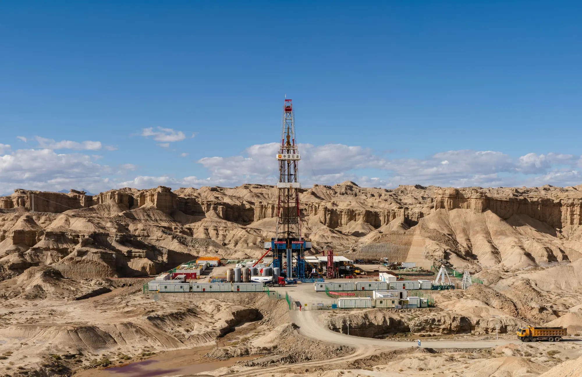 Drilling rig in a badlands landscape under a blue sky