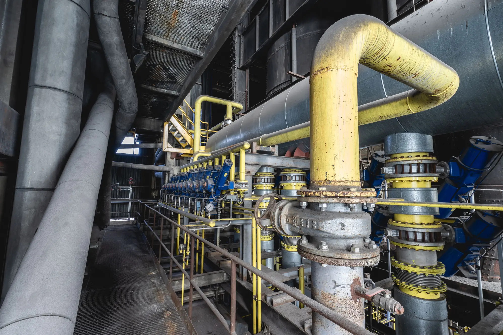 Machine room with yellow pipework, valves and pumps